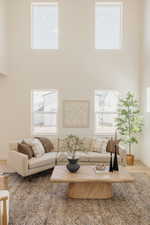 Great room featuring soaring ceilings, a two-story window arrangement, light wood-finish flooring, and a large area rug with a detailed pattern