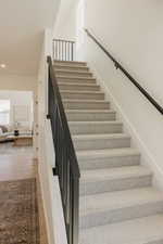 Staircase featuring light gray carpeting and matte black railings with vertical balusters