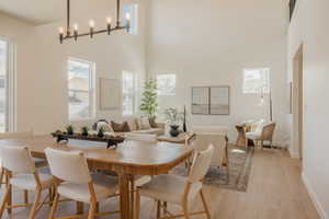 Open-concept living area with vaulted ceilings, a linear chandelier, multiple windows, and wood-finish flooring throughout