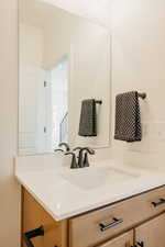 Bathroom vanity with an integrated sink, light-toned countertop, and matte black faucet