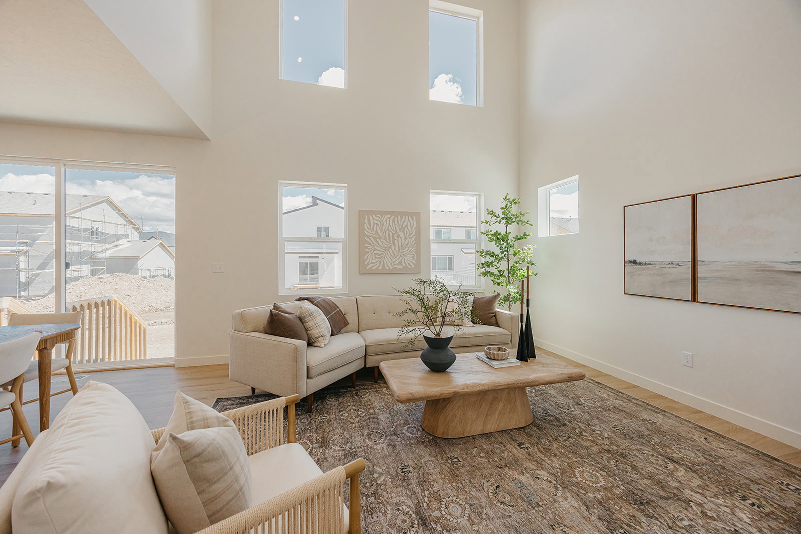 Vaulted ceiling great room featuring wood-finish flooring, multiple windows, and a sliding glass door