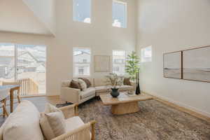 Vaulted ceiling great room featuring wood-finish flooring, multiple windows, and a sliding glass door