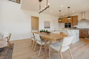 Open-concept dining area featuring wood-finish flooring, a contemporary linear chandelier, and recessed lighting