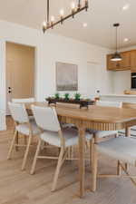 Open-concept dining area featuring wood-finish flooring, a linear chandelier, recessed lighting, and a kitchen island with pendant lighting
