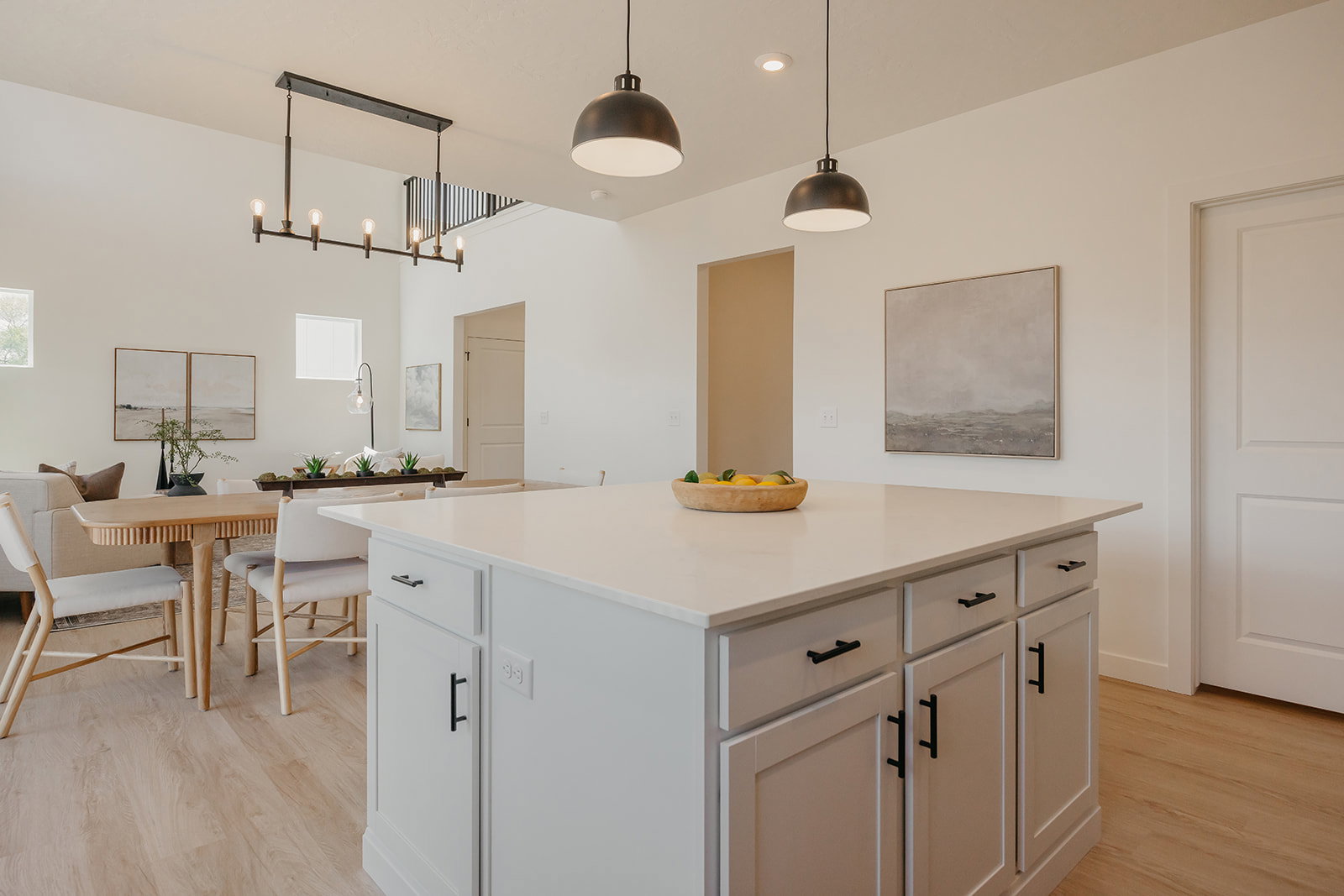 Kitchen island featuring a light-toned countertop, shaker-style cabinetry with black hardware, and pendant lighting