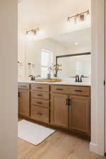 Double vanity with light wood-finish cabinetry and matte black hardware
