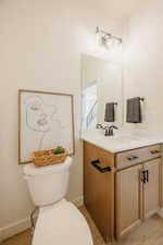 Bathroom with a light wood-finish vanity, white countertop, and integrated sink