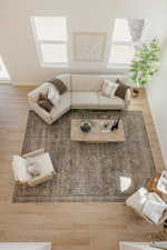 Open-concept living area featuring high ceilings with upper windows, wood-finish flooring, and a patterned area rug