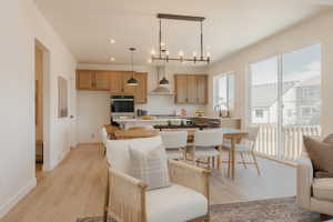 Open-concept kitchen and dining area featuring wood-finish flooring, light wood cabinetry, a tile backsplash, and an integrated wall oven