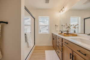 Bathroom featuring a double vanity with light wood-finish cabinetry, white countertops, and black hardware