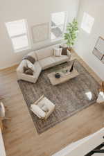 Living area featuring light wood-finish flooring, high ceilings, multiple windows, and a patterned area rug