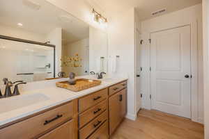 Dual vanity with integrated sinks, white countertops, wood-finish cabinetry, and black hardware