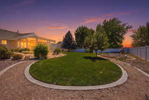 Landscaped backyard featuring a circular lawn area, gravel pathways, and a built-in fire pit