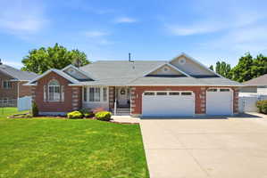Traditional-style residence featuring a brick facade with stone accents, a gray shingled roof, a concrete driveway, and an attached two-car garage