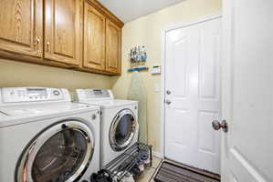 Dedicated laundry area featuring wood cabinetry, tiled flooring, and a white paneled door