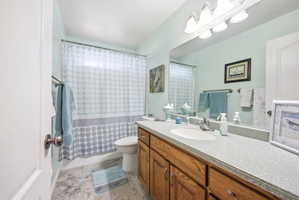 Bathroom featuring a wood-finish vanity with a single sink and light-colored countertop