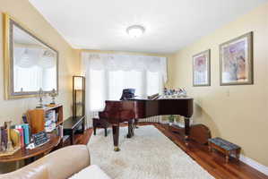 Living space featuring wood-finish flooring, a large bay window with white valances, and light-toned wall paint