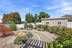 Expansive xeriscaped backyard featuring a gravel path, natural stone pavers, and mature plantings