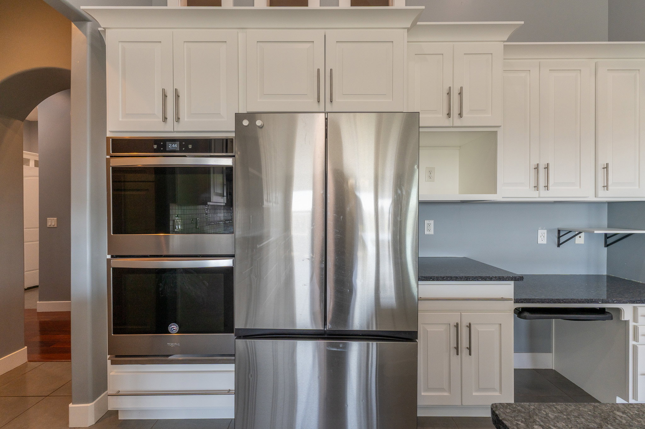 Kitchen featuring stainless steel appliances, white cabinetry, dark countertops, and a double wall oven