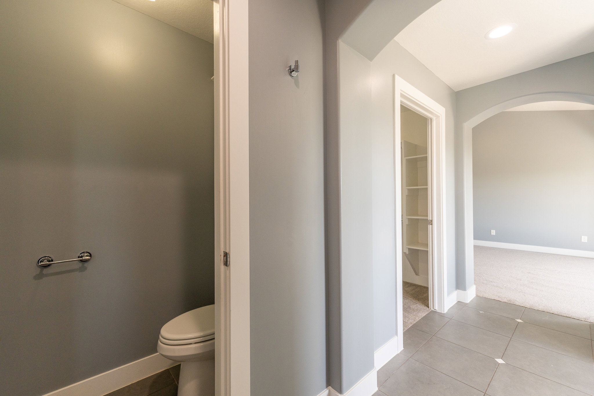 Hallway with tile flooring, recessed lighting, arched doorway, and a built-in shelving unit
