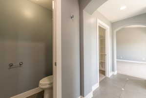 Hallway with tile flooring, recessed lighting, arched doorway, and a built-in shelving unit