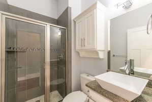 Modern bathroom featuring a rectangular vessel sink, granite-finish countertop, and white shaker-style cabinetry