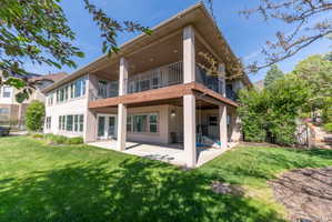 Two-story property featuring an upper-level balcony with metal railings and a lower-level patio