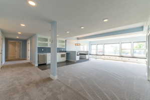 Open-concept living area featuring light gray carpeting and recessed lighting