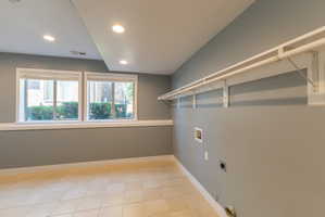 Laundry room featuring tile flooring, dual windows, recessed lighting, and wall-mounted shelving with hanging rods