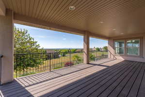 Spacious covered deck featuring composite decking, recessed lighting, substantial support columns, and an expansive landscape backdrop