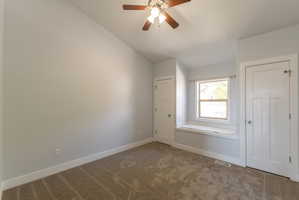 Carpeted room featuring a window with a built-in window seat, a ceiling fan with light fixture, and two panel doors