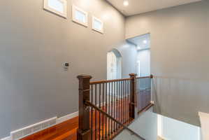 Staircase featuring wood-finish treads and risers, dark wood newel posts, and wrought iron balusters