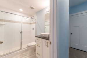 Modern bathroom featuring a sliding glass shower enclosure, white subway tile with a decorative accent band, and a white floating vanity with a vessel sink