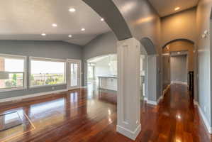 Expansive living area featuring rich wood-finish flooring, recessed lighting, and a vaulted ceiling