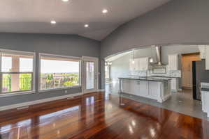 Spacious living area featuring rich wood-finish flooring, recessed lighting, and a vaulted ceiling
