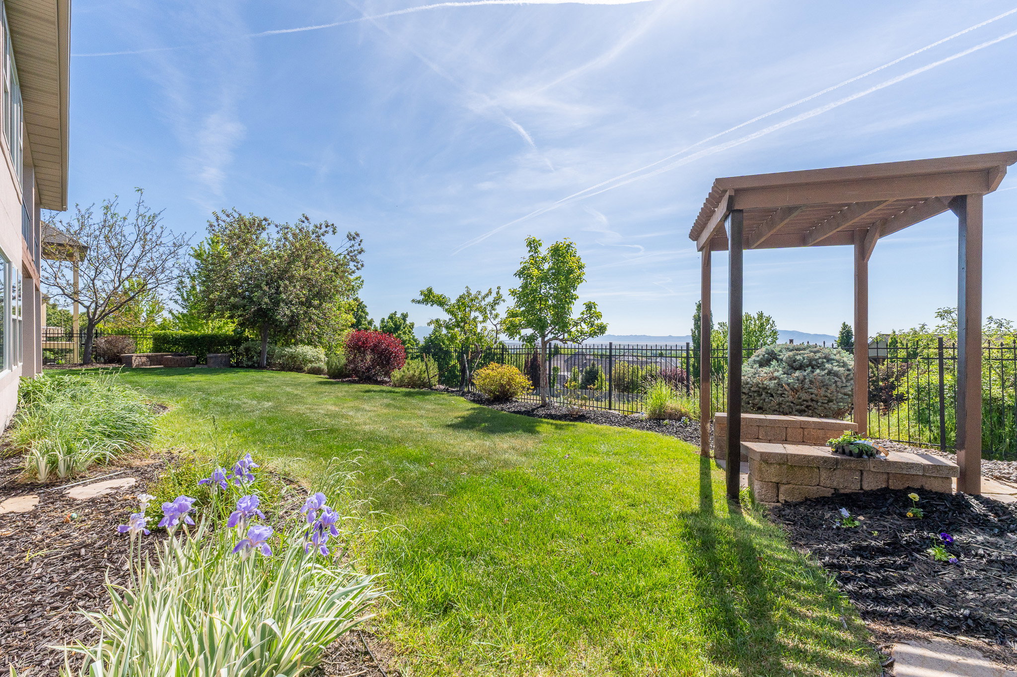 Expansive green lawn with a pergola feature and stone retaining wall