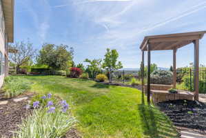 Expansive green lawn with a pergola feature and stone retaining wall