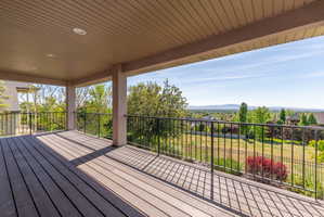 Expansive covered deck featuring composite decking, recessed lighting, and black metal railings