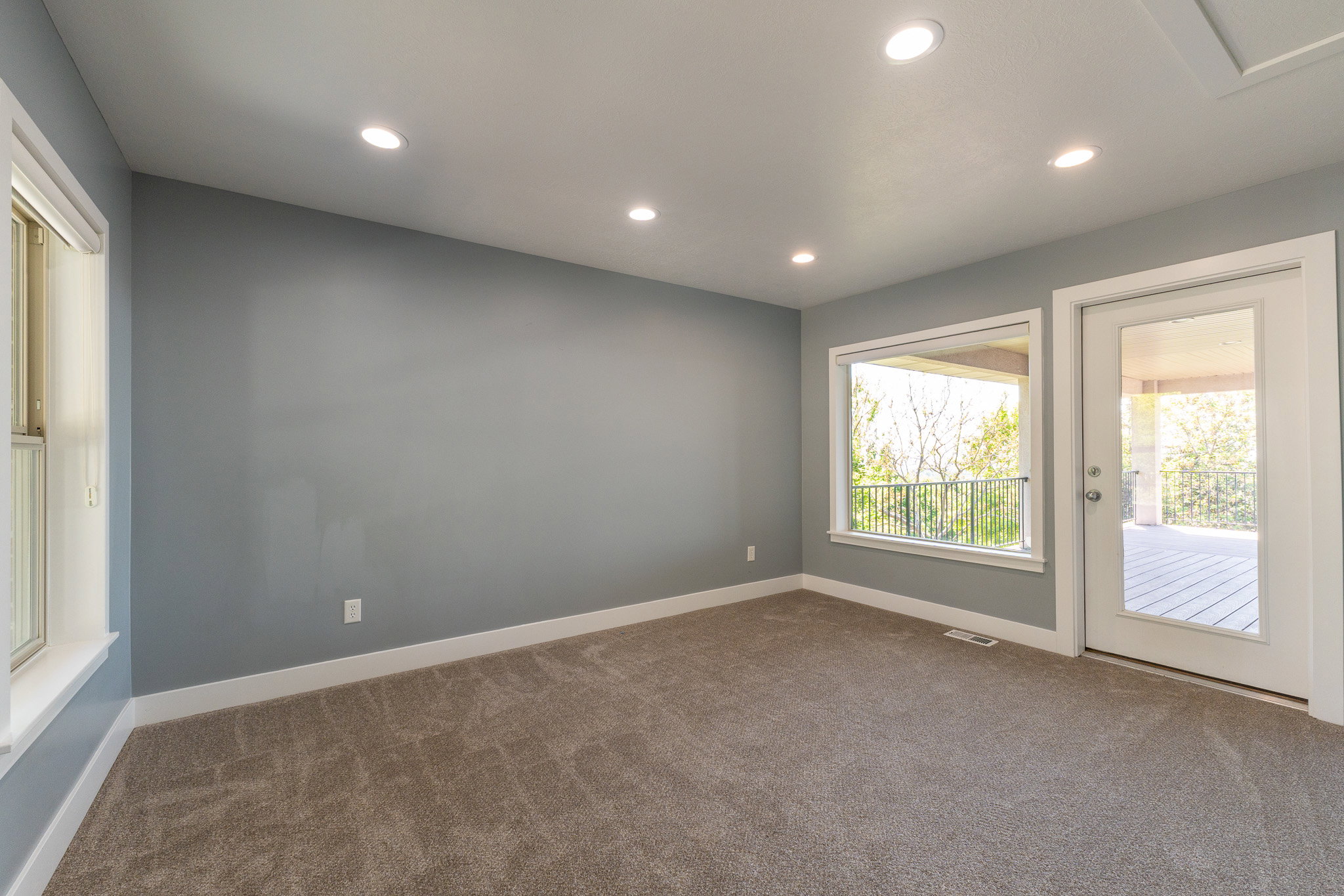 Spacious room featuring neutral carpeting, recessed ceiling lighting, and light grey wall paint