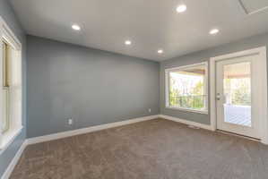 Spacious room featuring neutral carpeting, recessed ceiling lighting, and light grey wall paint