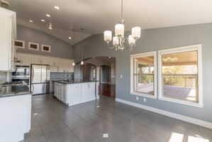 Expansive kitchen and dining area featuring vaulted ceilings, recessed lighting, and a chandelier
