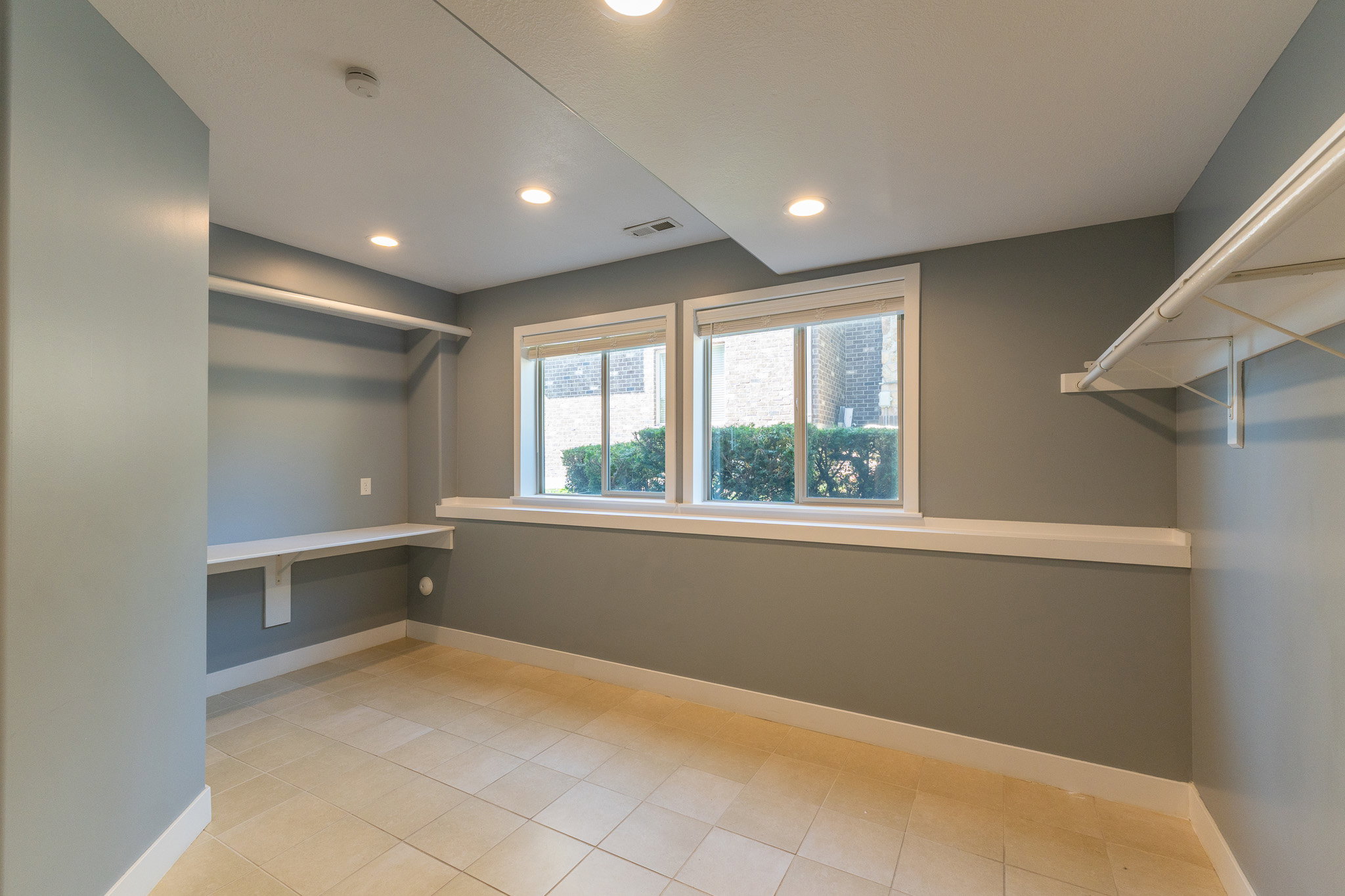 Room featuring light-toned tile flooring, dual windows with white trim, and recessed ceiling lighting