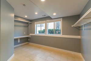 Room featuring light-toned tile flooring, dual windows with white trim, and recessed ceiling lighting