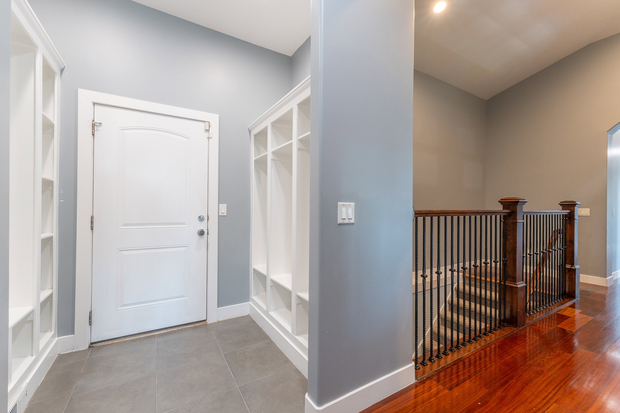 Entryway featuring built-in white shelving units, a white paneled door, and gray tile flooring