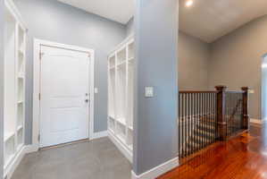 Entryway featuring built-in white shelving units, a white paneled door, and gray tile flooring