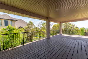 Spacious covered deck featuring composite decking, recessed lighting, and black metal railings, offering an outdoor extension of living space