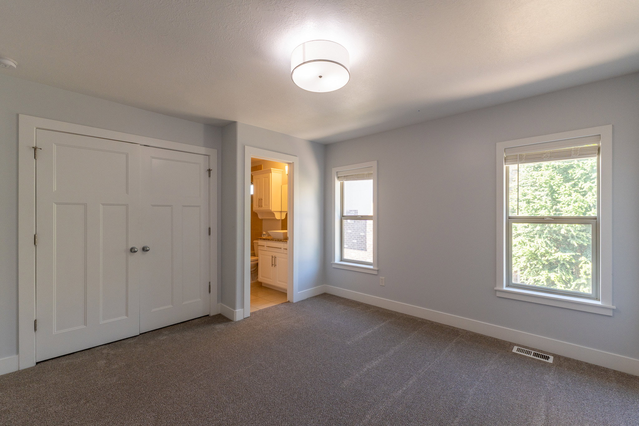 Bright room featuring two windows, neutral gray walls, and plush carpeting