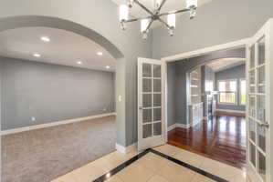 Entryway featuring tile flooring with a dark border accent, leading to an arched opening and double French doors