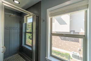 Glass-enclosed shower with a rain shower head, mosaic tile accents, and a built-in window