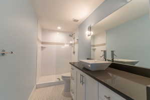 Modern bathroom featuring a vanity with a vessel sink, dark countertop, and white cabinetry